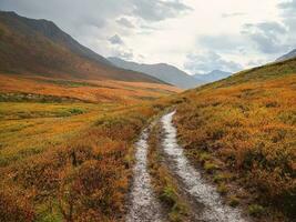 Wet off road through the rainy summer mountain plateau. Terrible thunderclouds have hung over the autumn valley. The sky before a thunderstorm with thunderclouds. photo