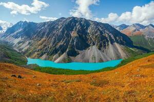 azul montaña lago en el caldera. montaña rango en contra un azul nublado cielo. caldera de un extinto volcán es rodeado por un montaña rango. en el Valle allí es un azul lago con escarpado rocoso costas foto