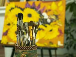 Art brushes in a cup holder on a colored yellow background. photo