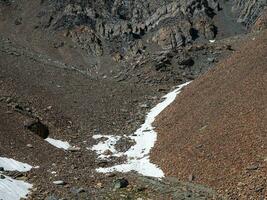 minimalista montaña paisaje con glaciar en rocoso colina. escaso nieve en aprobar. hermosa verano ver a tierras altas naturaleza. montaña de piedras en alto altitud. foto