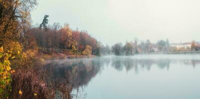 The village is in a fog. Panoramic view of morning haze over surface of the lake near Gatchina city photo