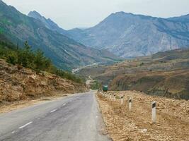 Asphalt road stretching into the distance.  Hot asphalt road through the hills and mountains. Turn on an empty mountain road. Old cracked asphalt mountain road in Dagestan. photo