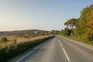 An empty country road in the autumn hills with cottages. photo