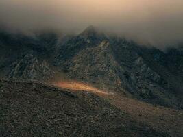 místico ligero en el brumoso oscuro montañas. dramático cielo en monte foto