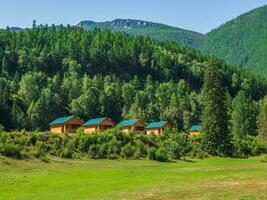 Collective camping, tourist complex, wooden guest houses against the background of fir-covered high mountains. photo