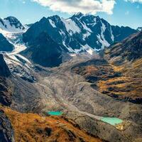 Awesome alpine panoramic view from pass to mountain valley in sunlight and great mountain silhouettes on horizon. Colorful green landscape with silhouettes of big rocky mountains and epic deep gorge. photo