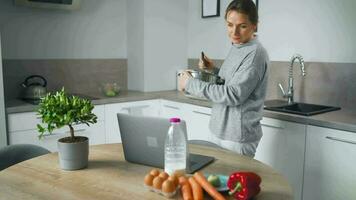 Woman looking recipe online while cooking video