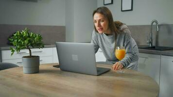 mujer en pie en hogar acogedor cocina utilizar ordenador portátil hacer Lanza libre trabajar, chateando con alguien, respondiendo correo electrónico. concepto de remoto trabajo video