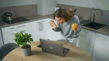 mujer en pie en hogar acogedor cocina utilizar ordenador portátil hacer Lanza libre trabajar, chateando con alguien, respondiendo correo electrónico. concepto de remoto trabajo video