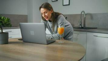 Woman standing in home cozy kitchen use laptop do freelance work, chatting with someone, answering e-mail. Concept of remote work video