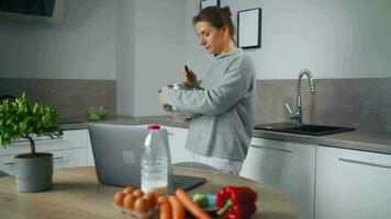 mujer mirando receta en línea mientras Cocinando video