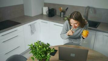 Woman standing in home cozy kitchen use laptop do freelance work, chatting with someone, answering e-mail. Concept of remote work video