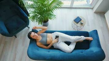 Overhead shot of relaxed woman in wireless headphones listening to music and using mobile apps on smartphone with green mock-up screen video