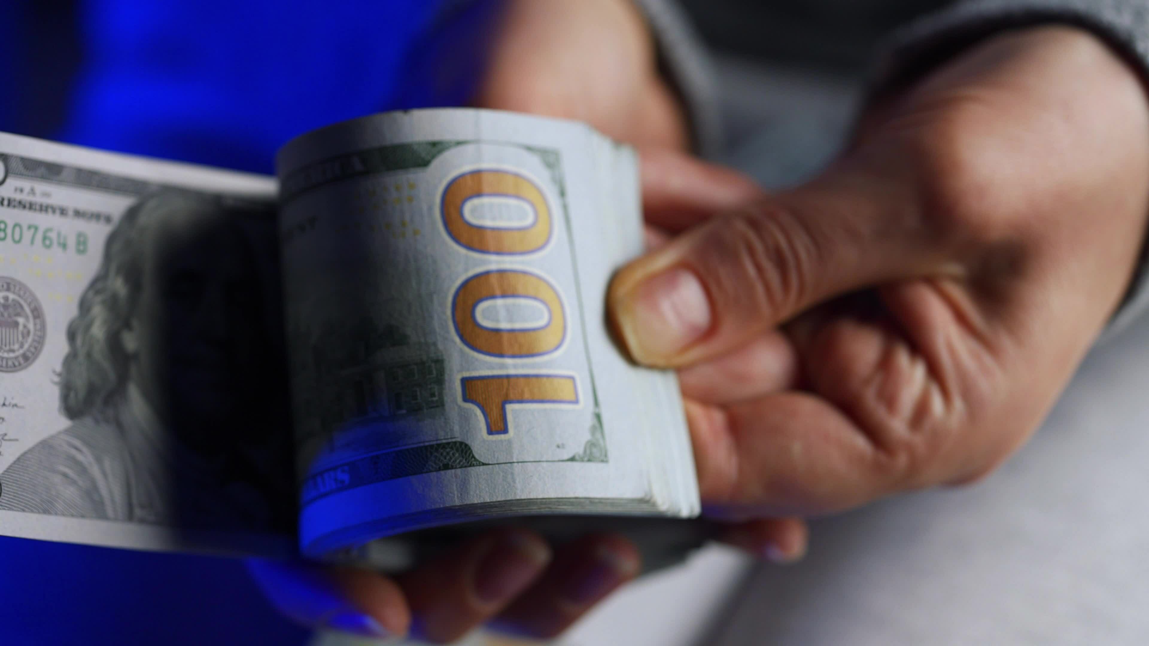 Hands checks US Dollar bills or counting in cash against the backdrop