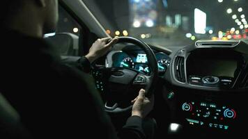 Man driving car through the streets of night city. View from the back seat of the car video