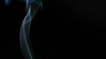 Abstract smoke rises up in beautiful swirls on black background. video