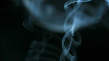 Abstract smoke rises up in beautiful swirls on black background. video