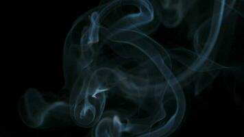 Abstract smoke rises up in beautiful swirls on black background. video