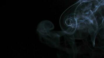 Abstract smoke rises up in beautiful swirls on black background. video