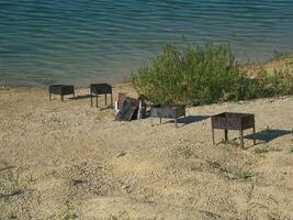 hierro parilla. izquierda basura en el apuntalar de el lago. humano contaminación de naturaleza foto