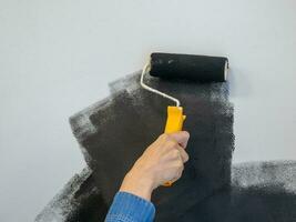 Woman painting a wall in black. Copy space. photo