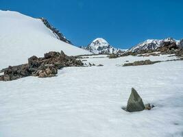 Sharp rocks. Highland scenery with sharpened stones of unusual shape. Awesome scenic mountain landscape with big cracked pointed stones closeup among snow under blue sky in sunlight. photo