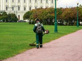 Lawn mower from the back at work. City service, maintenance of the city lawn in the Park. photo