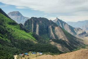 Sharp rocks. Colorful sunny green landscape with silhouettes of big rocky mountains and epic deep gorge with village under the rock. photo