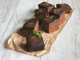 Freshly baked classic brownie on parchment are laid out on a whi photo