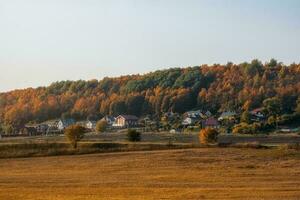 Sunny evening landscape with farmland ready for planting, with a village on a hill in the autumn background photo