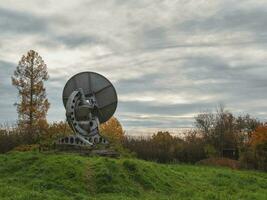 Clásico telescopio un grande satélite plato en un antecedentes de observación bosque y nublado cielo, Radar en el pasado. tecnología concepto, buscar para extraterrestre vida, escuchas telefónicas de espacio. foto