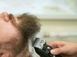 guarnición barba con tijeras en un Barbero tienda. cerca arriba. foto