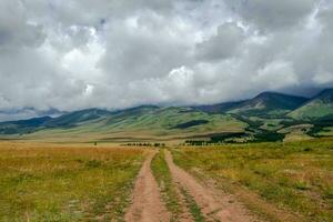 Summer path through mountains. Trekking mountain trail. Atmospheric rural minimalist alpine landscape with stony footpath among grasses in highlands. Pathway uphill. Way up mountainside. photo