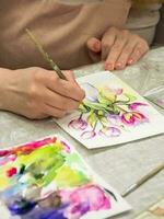 Brush in the hands of the artist, watercolor painting, creativity with many colors. Vertical view. photo