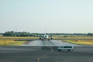 Transfer from the airport. White minibus is waiting for guests in front of the plane. High service, reception of guests. photo