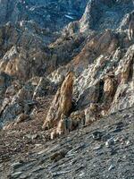 increíble escénico montaña paisaje con grande agrietado puntiagudo piedras de cerca en luz de sol. agudo rocas antecedentes. vertical vista. foto