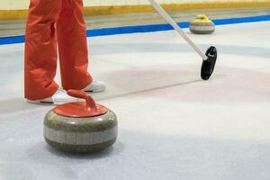 Escoba y Roca para curling en hielo de un adentro pista. foto