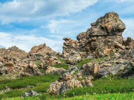 Sunny highland scenery with big stones of unusual shape. Awesome scenic mountain landscape with big cracked stones closeup among grass under blue sky in sunlight. photo