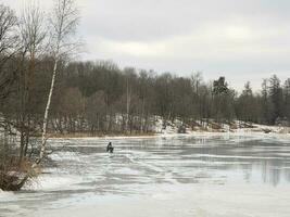Dangerous fishing on wet spring ice. Fisherman on wet melting ice. photo