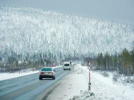 Polar traffic of cars on a slippery road among snow-covered hills. photo