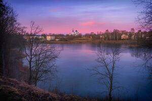 Beautiful purple sunset on the lake. The temple on the hill. The ancient Russian city of Gatchina photo