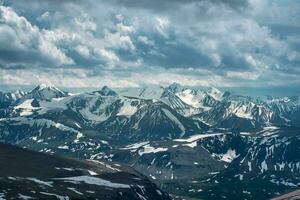 Mountain peaks under a dramatic sky natural background. Wonderful dramatic landscape with big snowy mountain peaks above low clouds. Atmospheric large snow mountain tops in cloudy sky. photo