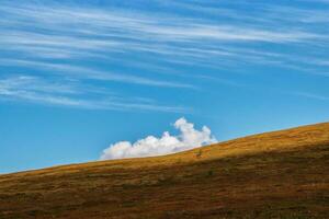 minimalista alpino paisaje con montaña silueta debajo azul cielo con solo grande nube. otoño Pendiente montaña y ligero cielo. mínimo naturaleza antecedentes con silueta de montaña debajo azul cielo. foto