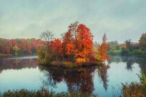 otoño bosque en un isla en el medio de un estanque en el Mañana niebla. místico Mañana otoño paisaje con niebla terminado el lago. foto