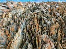 Texture of mountains. Dangerous sharp rocks. Sharp stones background. Abstract texture of split stone in dark gray color. Big cracked pointed stones closeup. photo