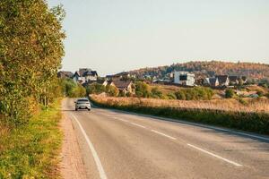 conducir a lo largo el otoño autopista de el país la carretera entre el hermosa otoño colinas con casas de campo un agudo giro en el la carretera foto