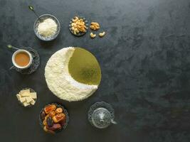 Biscuit cake sprinkled with white chocolate in the shape of a Crescent moon, served with dates and coffee cup photo