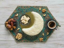 Festive food Ramadan background. Delicious homemade cake in the shape of a Crescent moon, served with dates and coffee cup photo