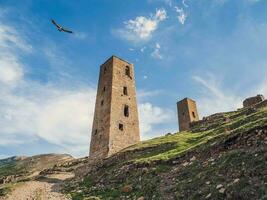 Beautiful summer view of ruins and towers of the aul ghost Goor in Dagestan in the evening light. Popular tourist destination. Russia. Bottom-up view. photo