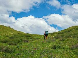 Solo hiking in the picturesque summer mountains. Heavy climb in the mountains with a backpack. Travel lifestyle, hiking hard track, adventure concept in summer vacation. photo